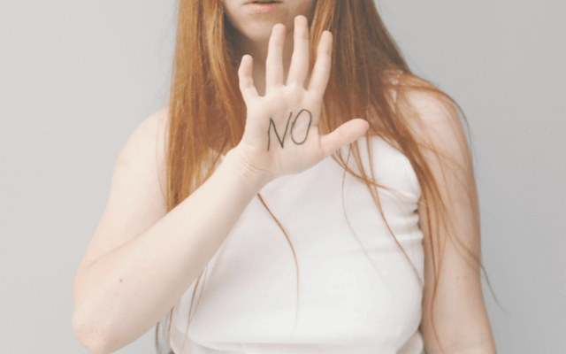 手のひらにNOと書いている女性