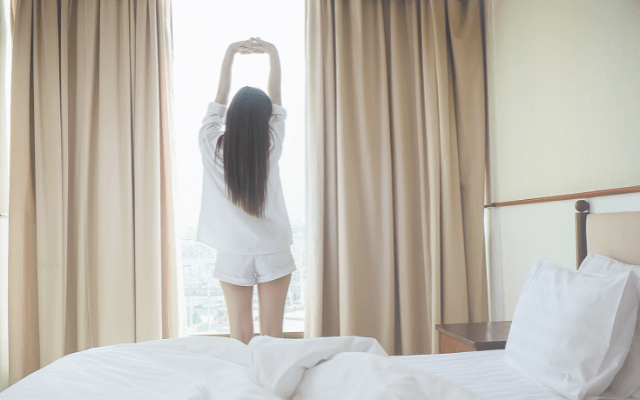 朝起きて伸びをしている女性